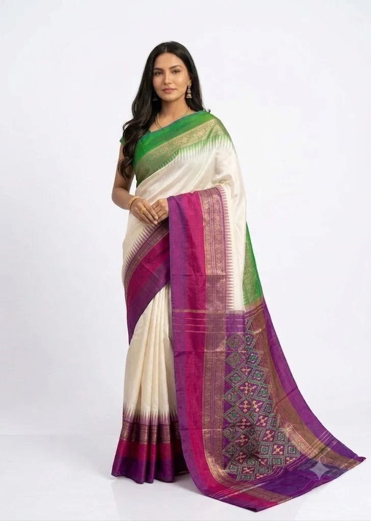 Elegant Indian woman standing in a pure Pochampally Ikat silk saree featuring an ivory white body, emerald green border, and royal magenta pallu.