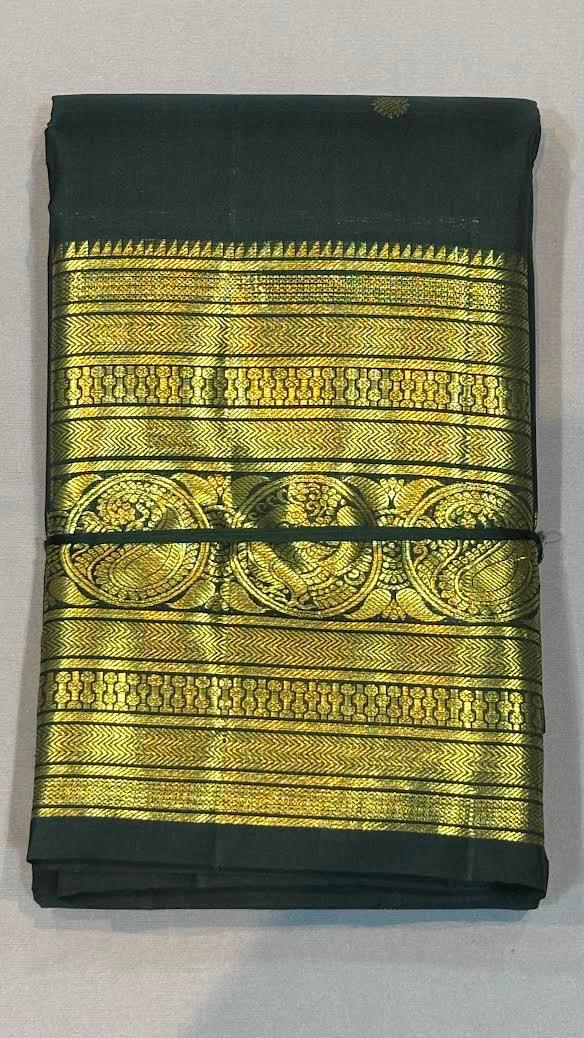 Close-up of the intricate gold zari pallu and traditional peacock motif border on a dark green pure Kanchipuram silk saree.