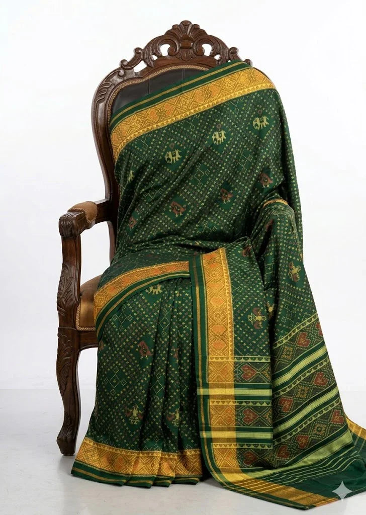 Close-up of a green Patola silk saree pallu featuring horizontal gold stripes and traditional red and yellow Ikat patterns