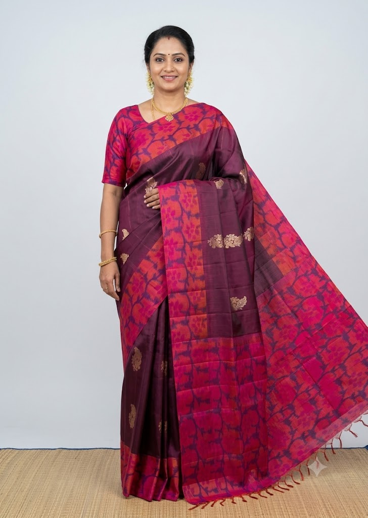 Traditional Indian woman wearing a deep wine Kanchi soft silk saree with golden leaf buttas and a bright magenta floral Jamdani weave border and blouse