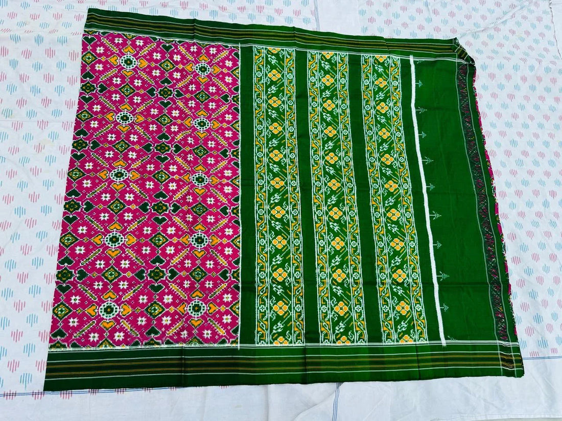 Flat lay of an authentic double ikat patola silk saree with a magenta geometric patterned body, bold green striped pallu, and Silk Mark certification