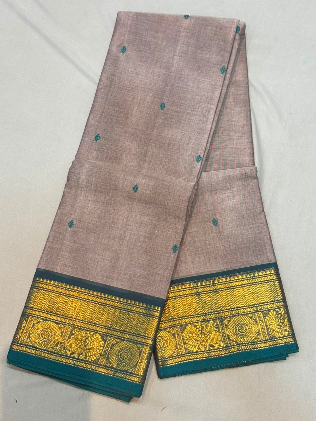 Handloom muted mauve pure Kanchi cotton saree with small teal woven buttas and rich teal border featuring gold zari peacock and chakra motifs
