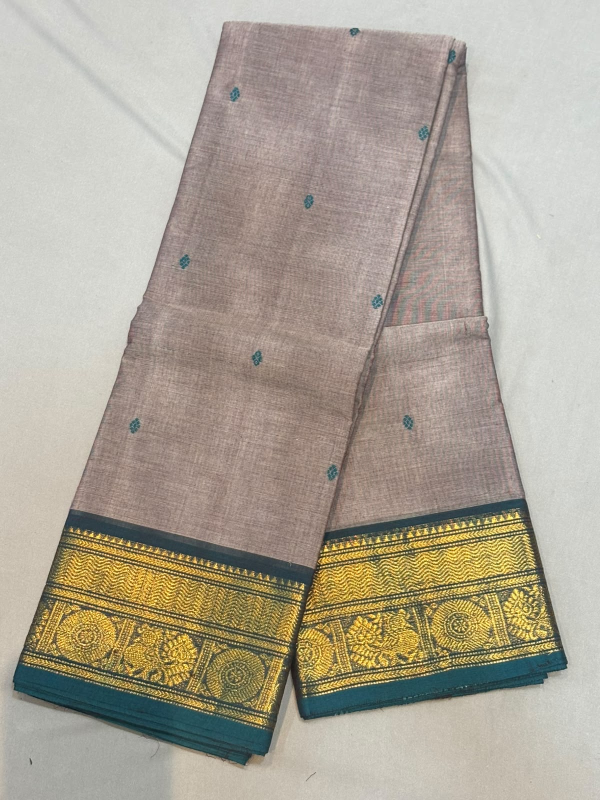 Handloom muted mauve pure Kanchi cotton saree with small teal woven buttas and rich teal border featuring gold zari peacock and chakra motifs