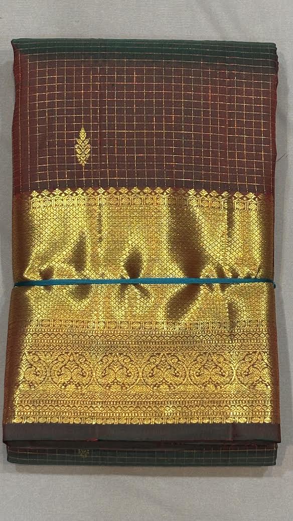A beautiful traditional woman gracefully sitting on a chair, draped in an authentic brown Kanchipuram pattu saree with gold zari borders and micro-checks