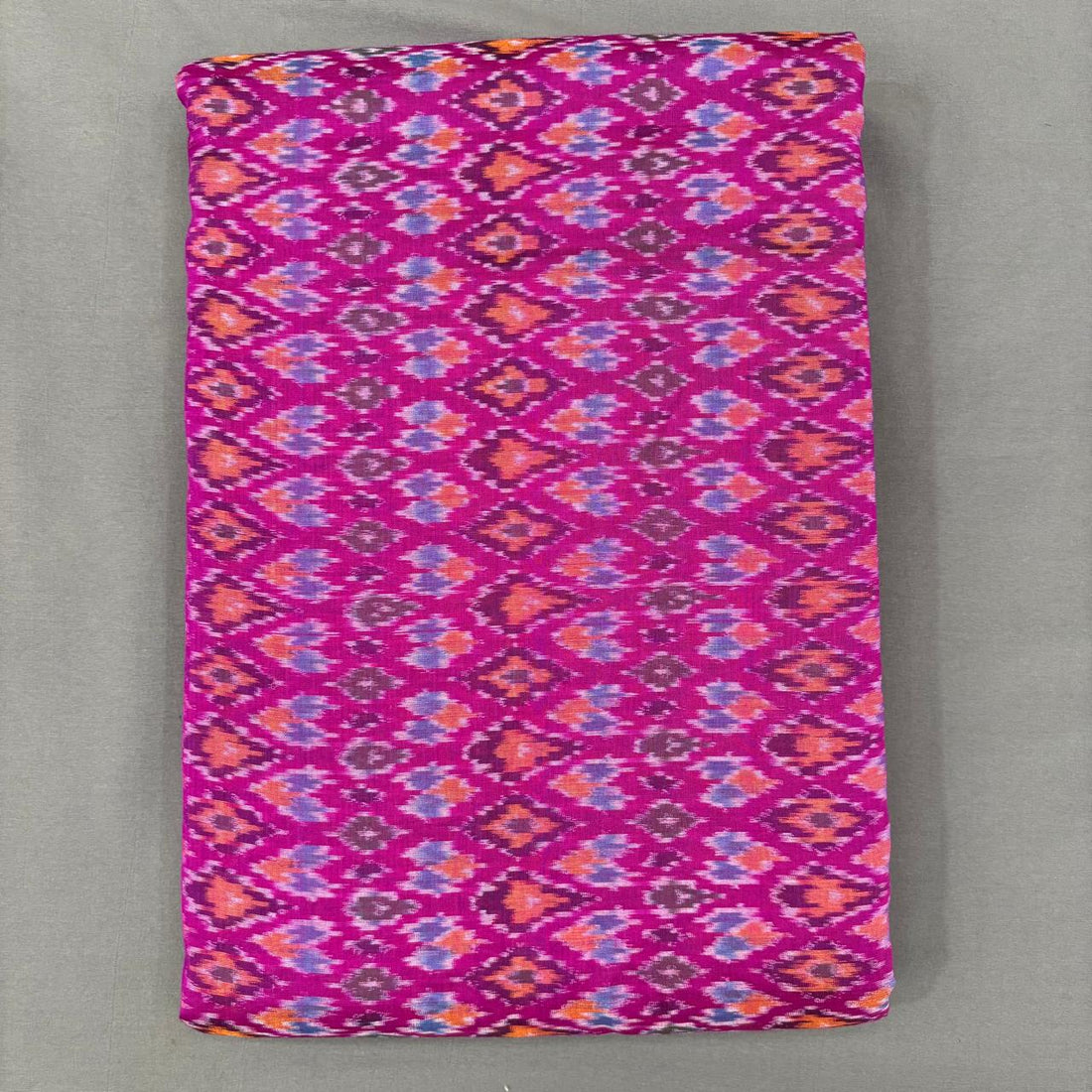 Bright pink, purple, and orange Pochampally ikkat sico unstitched dress material with a geometric diamond pattern.