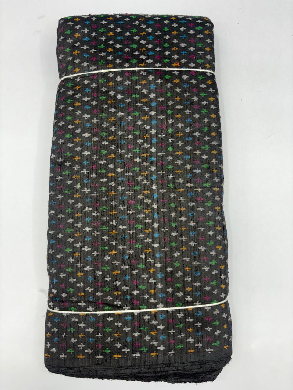 Folded bolt of black pure raw silk fabric featuring all-over multicolor geometric cross Ikat motifs with Silk Mark quality weave