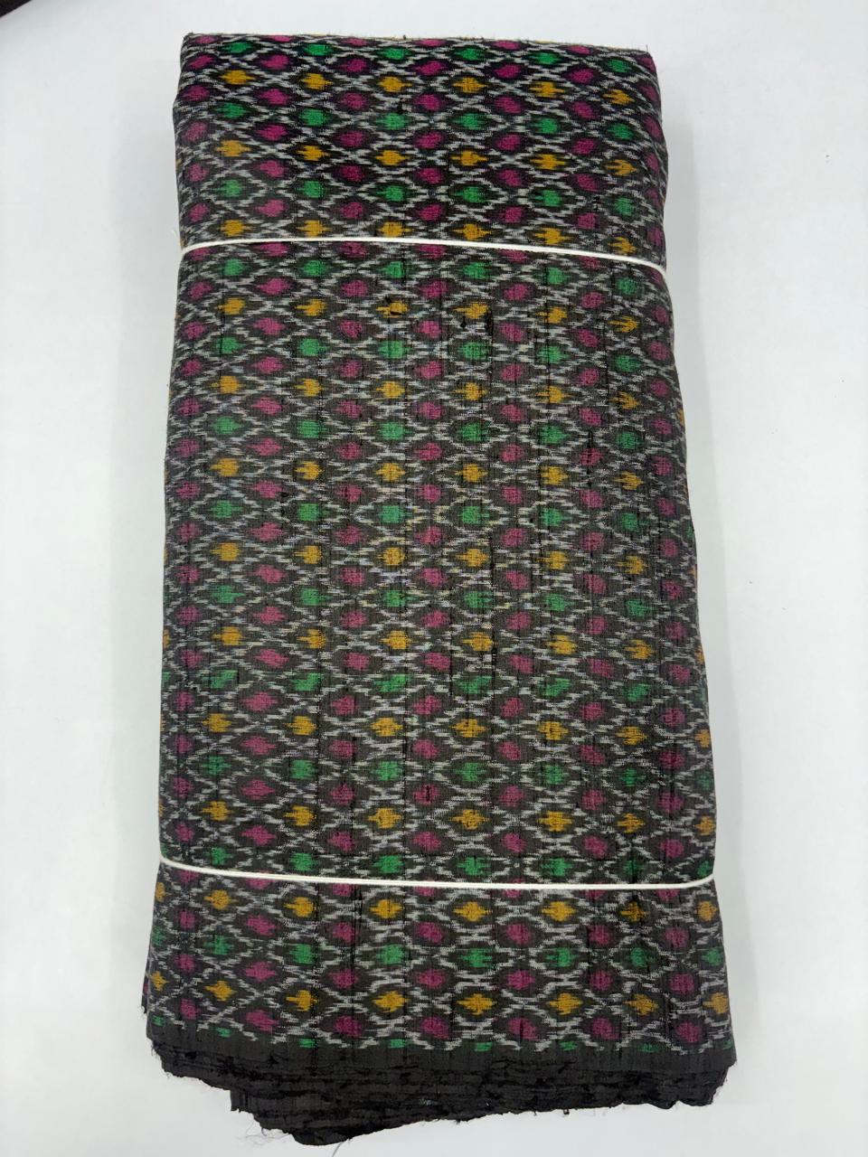 Folded bolt of charcoal black pure raw silk fabric featuring an intricate multicolor diamond lattice Ikat weave with Silk Mark authenticity