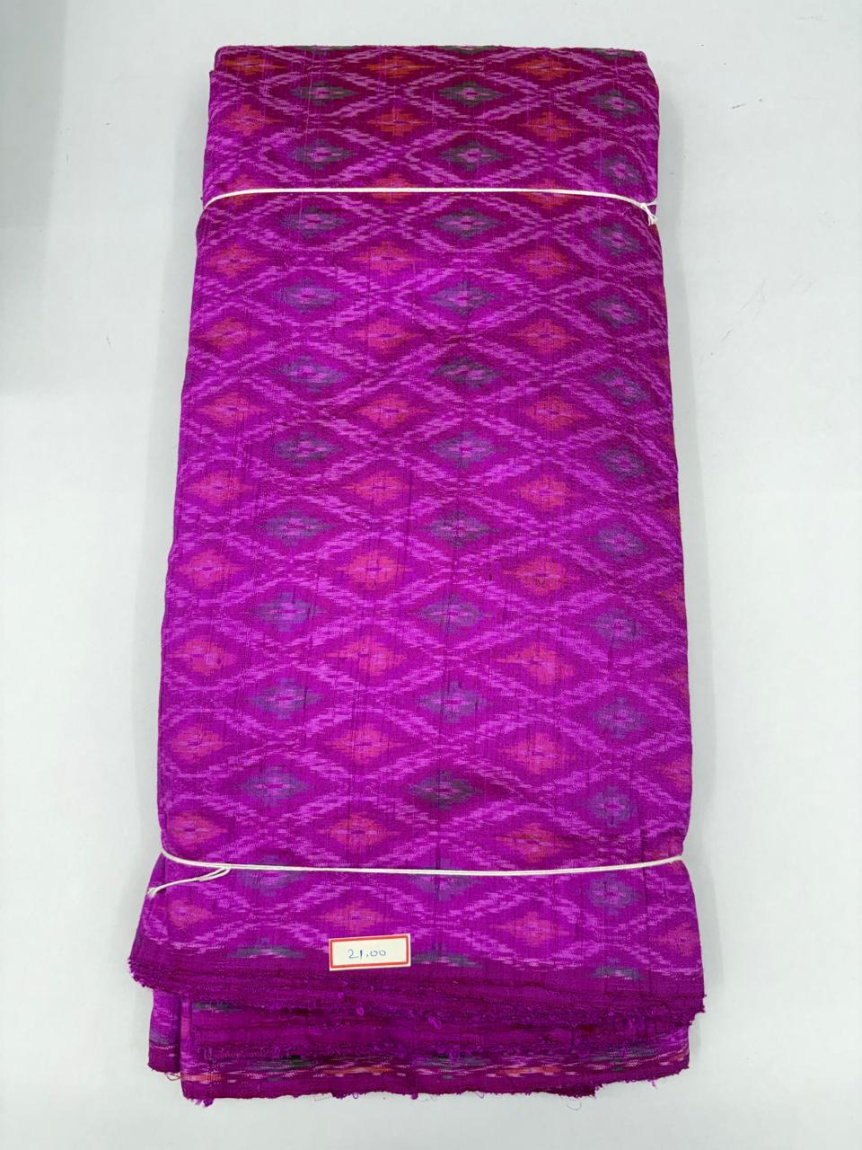 Folded bolt of magenta fuchsia pure raw silk fabric featuring geometric diamond lattice Ikat motifs with Silk Mark authenticity