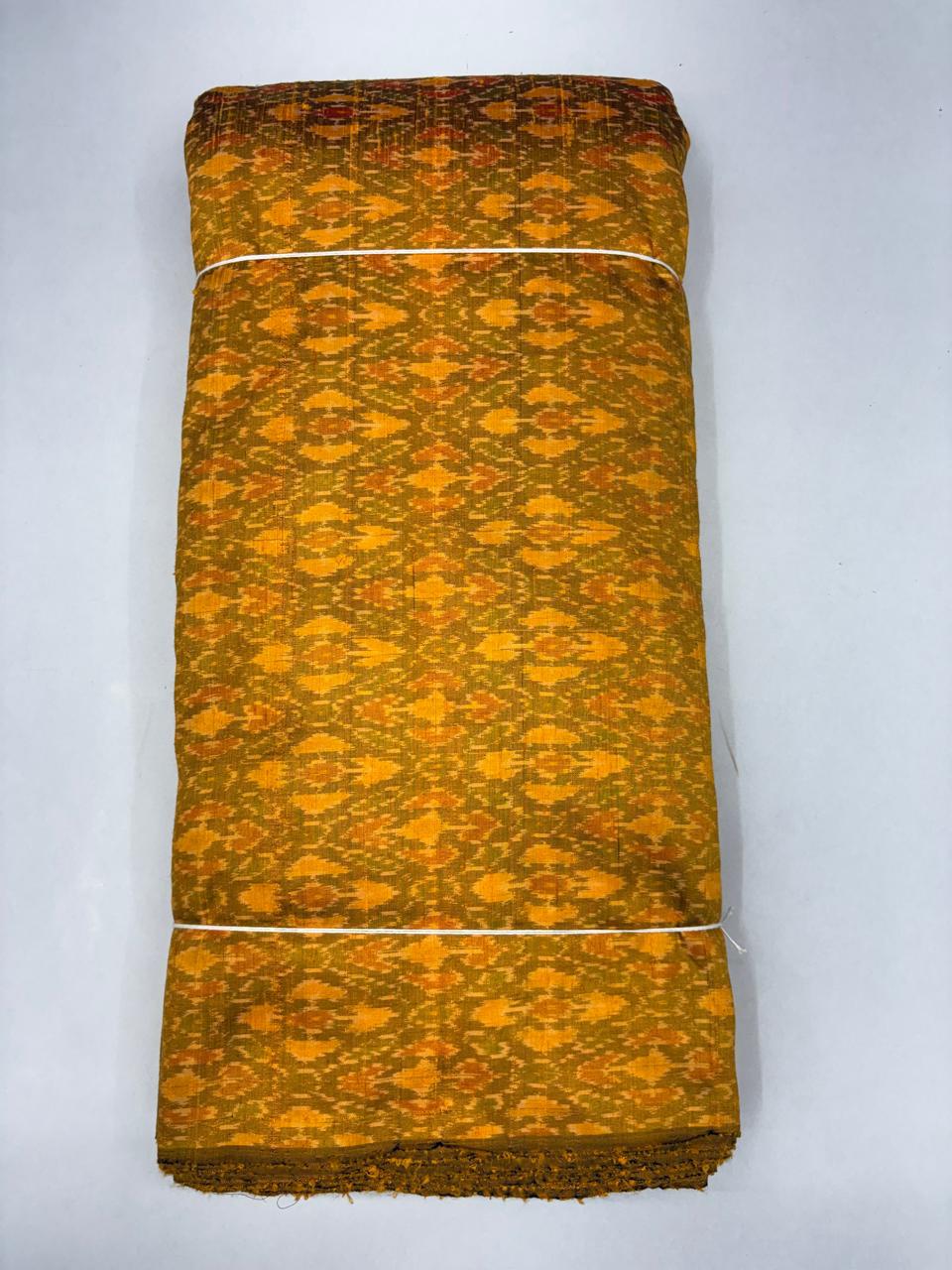 Folded bolt of mustard yellow pure raw silk fabric featuring an intricate geometric diamond Ikat weave with Silk Mark authenticity