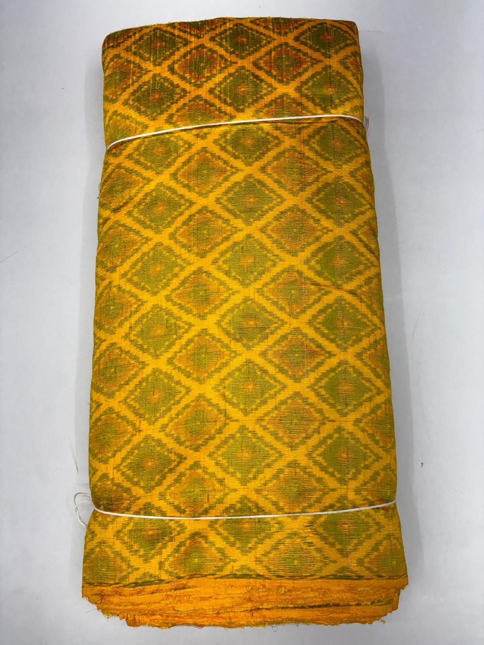 Folded bolt of vibrant mustard yellow pure raw silk fabric featuring an all-over diamond lattice Ikat weave with Silk Mark authenticity