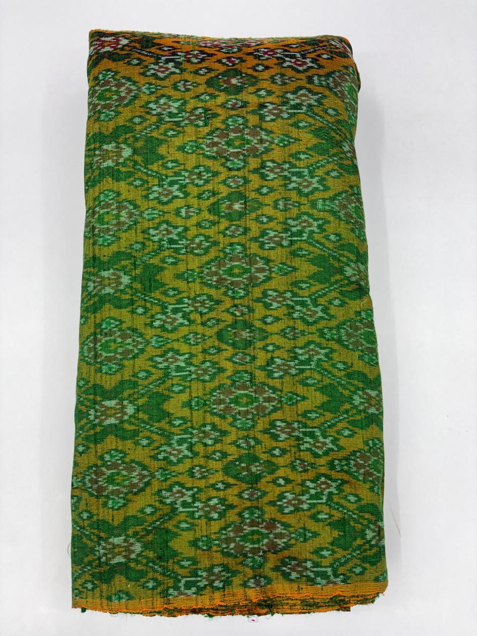 Folded bolt of olive green and mustard pure raw silk fabric featuring an intricate floral diamond Ikat weave with Silk Mark authenticity
