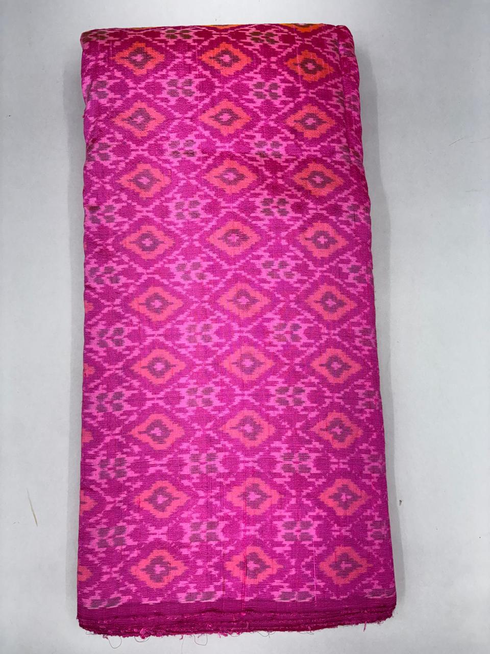 Folded bolt of vibrant rani pink pure raw silk fabric featuring geometric diamond Ikat motifs with Silk Mark authenticity