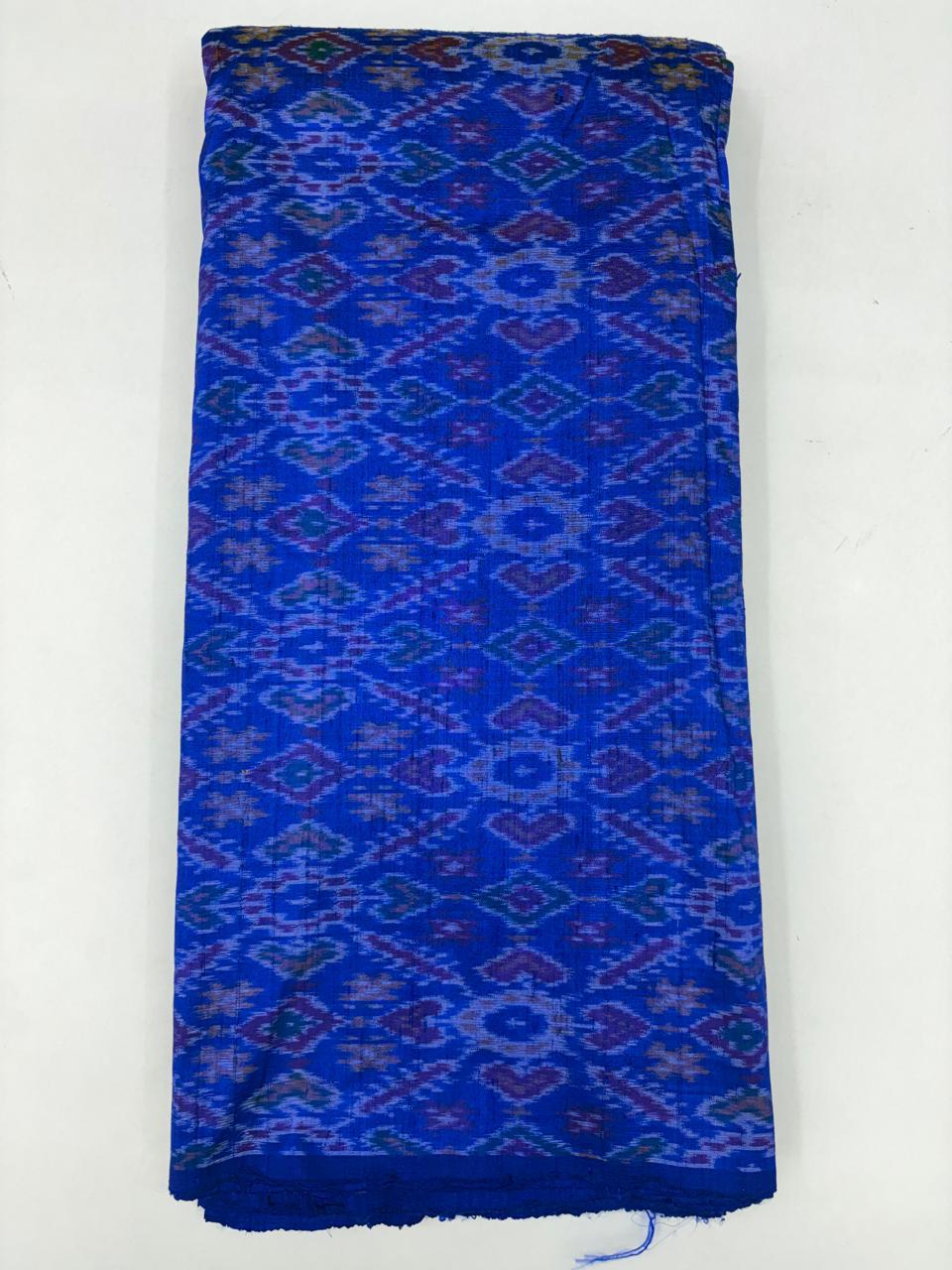 Folded bolt of vibrant royal blue pure raw silk fabric featuring traditional geometric diamond Ikat motifs and Silk Mark quality weave