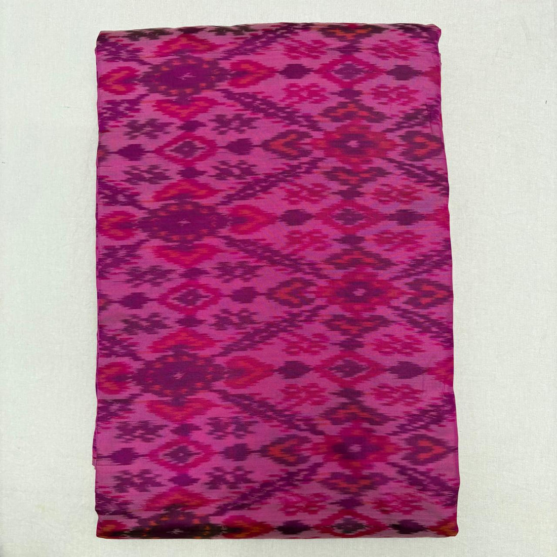 Folded mint sea green pure silk Ikat fabric featuring geometric diamond lattice with olive brown and mustard motifs with Silk Mark certification.