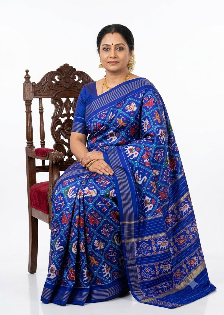 Model wearing a royal blue pure silk Ikkat Patola saree featuring traditional 9 figure navratna motifs and a gold zari border.