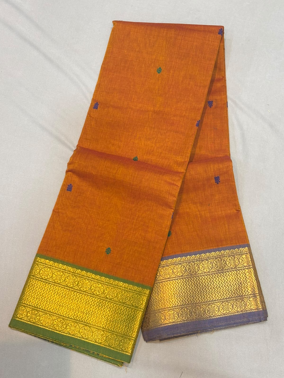 Handloom rust orange pure Kanchi cotton saree with small teal-blue buttas and dual Ganga Jamuna borders in olive green and slate lavender with gold zari