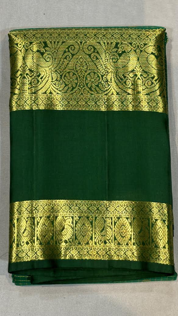 Close-up of an original green Kanchi pattu saree showing intricate gold zari checks on the body and a thick traditional gold border with peacock motifs.