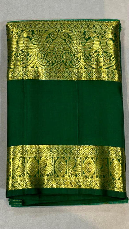 Close-up of an original green Kanchi pattu saree showing intricate gold zari checks on the body and a thick traditional gold border with peacock motifs.