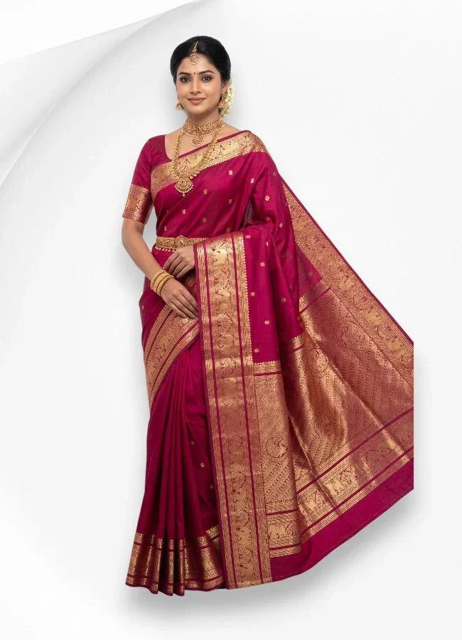 A beautiful Indian woman wearing a traditional magenta pure kanchipuram pattu silk saree featuring a heavy gold zari border with intricate elephant motifs.