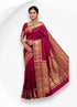 A beautiful Indian woman wearing a traditional magenta pure kanchipuram pattu silk saree featuring a heavy gold zari border with intricate elephant motifs.