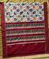Flat lay of a traditional Patola Ikat saree with a white body featuring elephant and parrot motifs, and a contrasting rich maroon pallu.