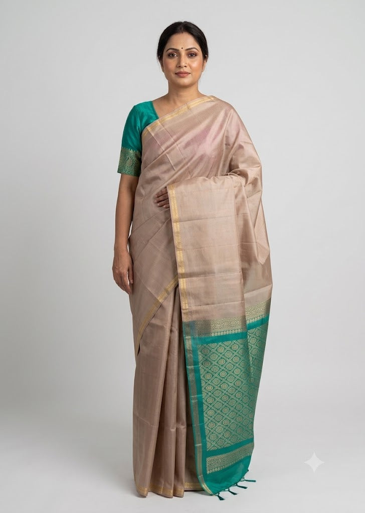 Indian woman wearing a beige silk saree with a teal green zari border and matching blouse against a neutral studio background
