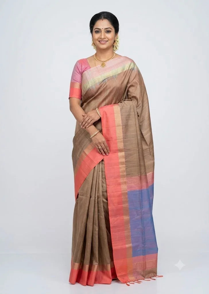 Indian model posing in a beige soft silk saree with coral pink border and blue contrast pallu