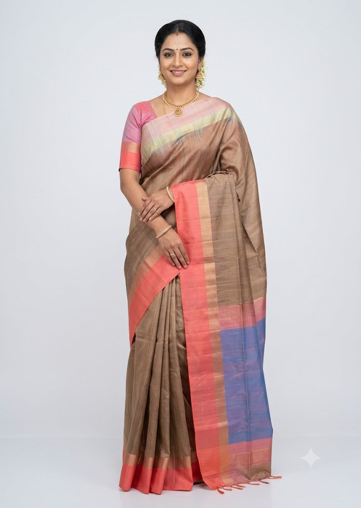 Indian model posing in a beige soft silk saree with coral pink border and blue contrast pallu