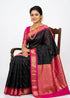Traditional Indian woman seated on a chair wearing a black Gadwal silk saree with a pink zari pallu and blouse