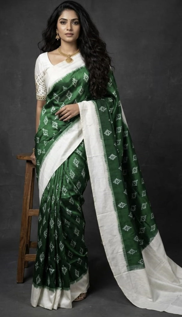 Indian woman standing in an elegant bottle green handloom ikkat silk saree with an off-white border and traditional jewelry