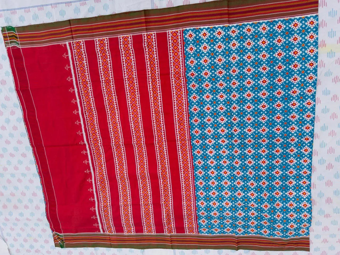 Flat lay of an authentic double ikat patola silk saree with a bright blue geometric patterned body, red striped pallu, and Silk Mark certification