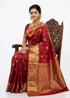 A South Indian woman elegantly draped in a traditional bright red pure kanchi pattu saree with gold coin motifs and a grand zari border, styled with traditional gold jewelry.
