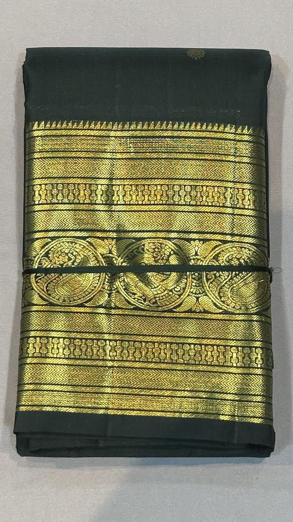 Close-up of the intricate gold zari pallu and traditional peacock motif border on a dark green pure Kanchipuram silk saree.