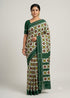 Model standing against a neutral backdrop wearing an authentic Telia Rumal handloom cotton saree in green and white with geometric patterns, traditional jewelry, and a bun with flowers.
