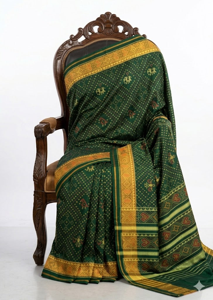 Close-up of a green Patola silk saree pallu featuring horizontal gold stripes and traditional red and yellow Ikat patterns