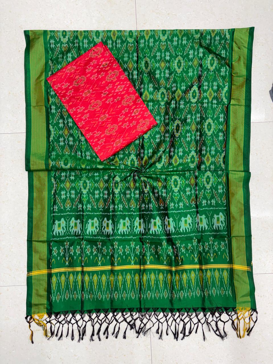 Emerald green and red Pochampally Ikat silk unstitched dress material set featuring handwoven geometric patterns, traditional elephant motifs on the border, and black and yellow tassel