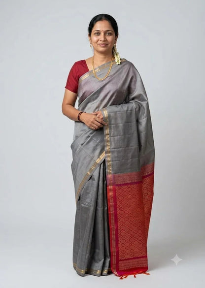 Traditional Indian woman wearing a grey silk saree with a crimson red blouse and golden zari pallu against a neutral grey background