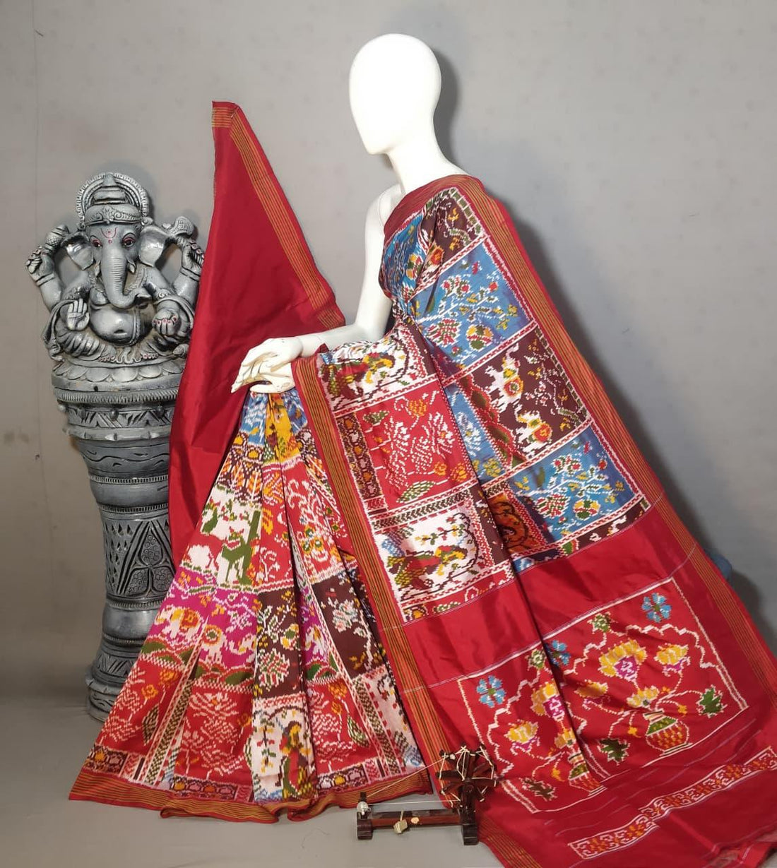 Handloom Pochampally Ikkat silk saree showcasing a multicolored grid pattern with traditional bird and elephant motifs on a red base featuring a Kalash border.