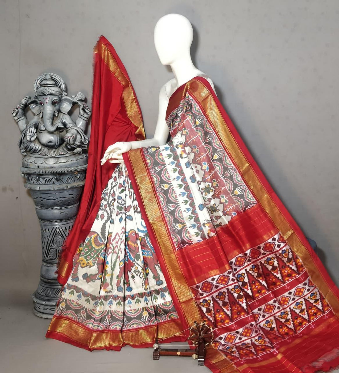 Handloom Pochampally Ikkat silk saree featuring an off-white body with traditional elephant motifs, a rich crimson red border, and a golden zari pattu edge.