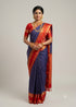 Elegant Indian woman wearing a handwoven royal blue Kanchipuram pure silk saree featuring a contrasting rich red border and pallu with elaborate gold zari work and traditional jewelry, verified with Silk Mark authentication."