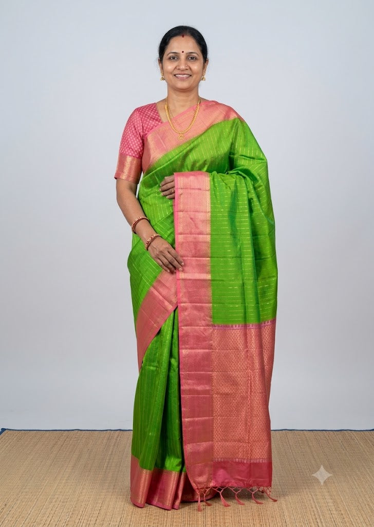 Indian model posing in a green Kanchi soft silk saree with a woven pink gold zari border and matching blouse