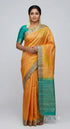 Indian woman wearing a traditional muted gold Kanchi soft silk saree paired with a teal green blouse and gold zari pallu against a neutral studio backdrop