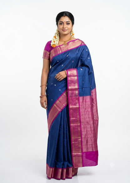 Traditional woman draped in a royal blue Kanchi soft silk saree with a magenta pink zari border against a plain white background