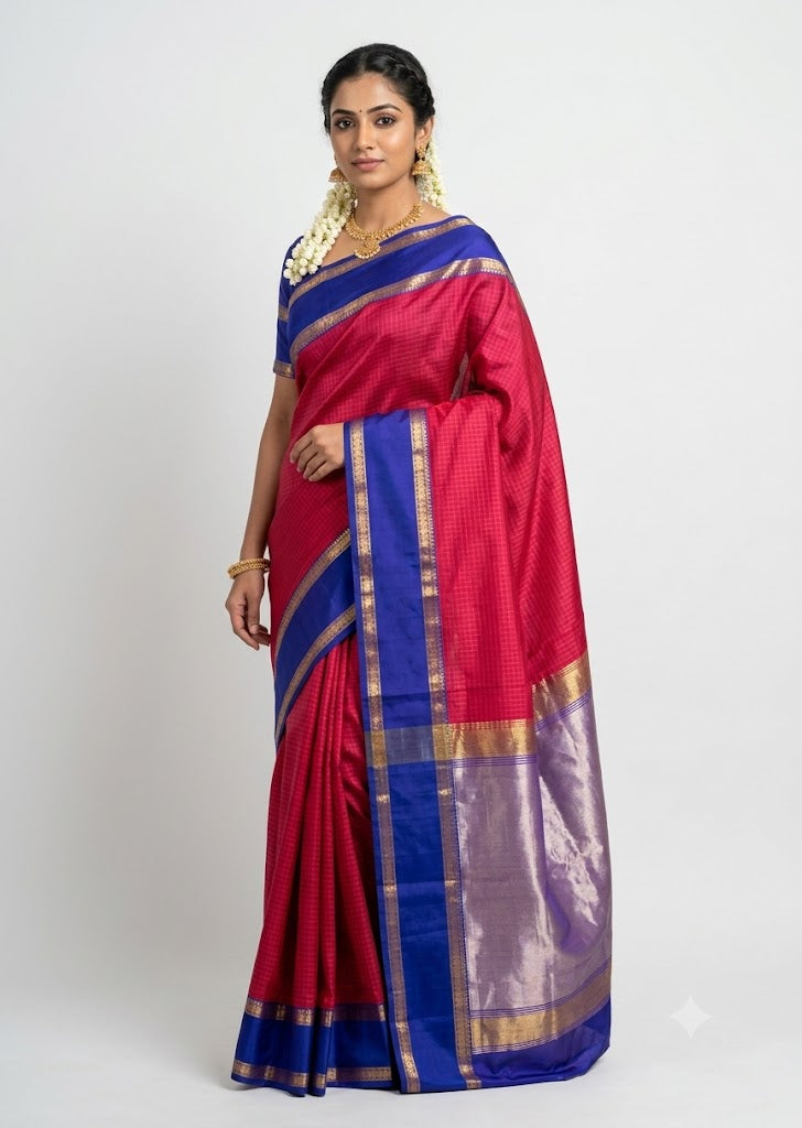 Indian model posing in a magenta red Kanchi checks silk saree with a royal blue border and silver zari pallu against a light gray backdrop