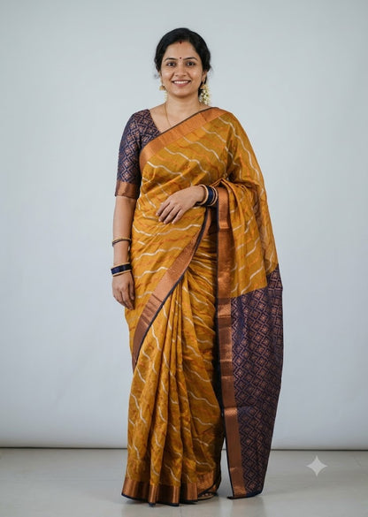Woman wearing a traditional mustard yellow Kuppadam Pattu saree with wavy zari stripes, copper zari border, and contrast navy blue floral brocade pallu and blouse.