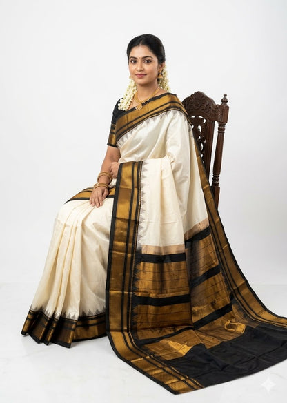 Traditional Indian woman sitting on a carved wooden chair, wearing an elegant off-white pure Gadwal silk saree featuring a contrasting black border and pallu with intricate gold zari temple motifs.