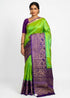 Model showcasing the front view of a parrot green Kanchi soft silk saree with a broad purple gold zari floral border.