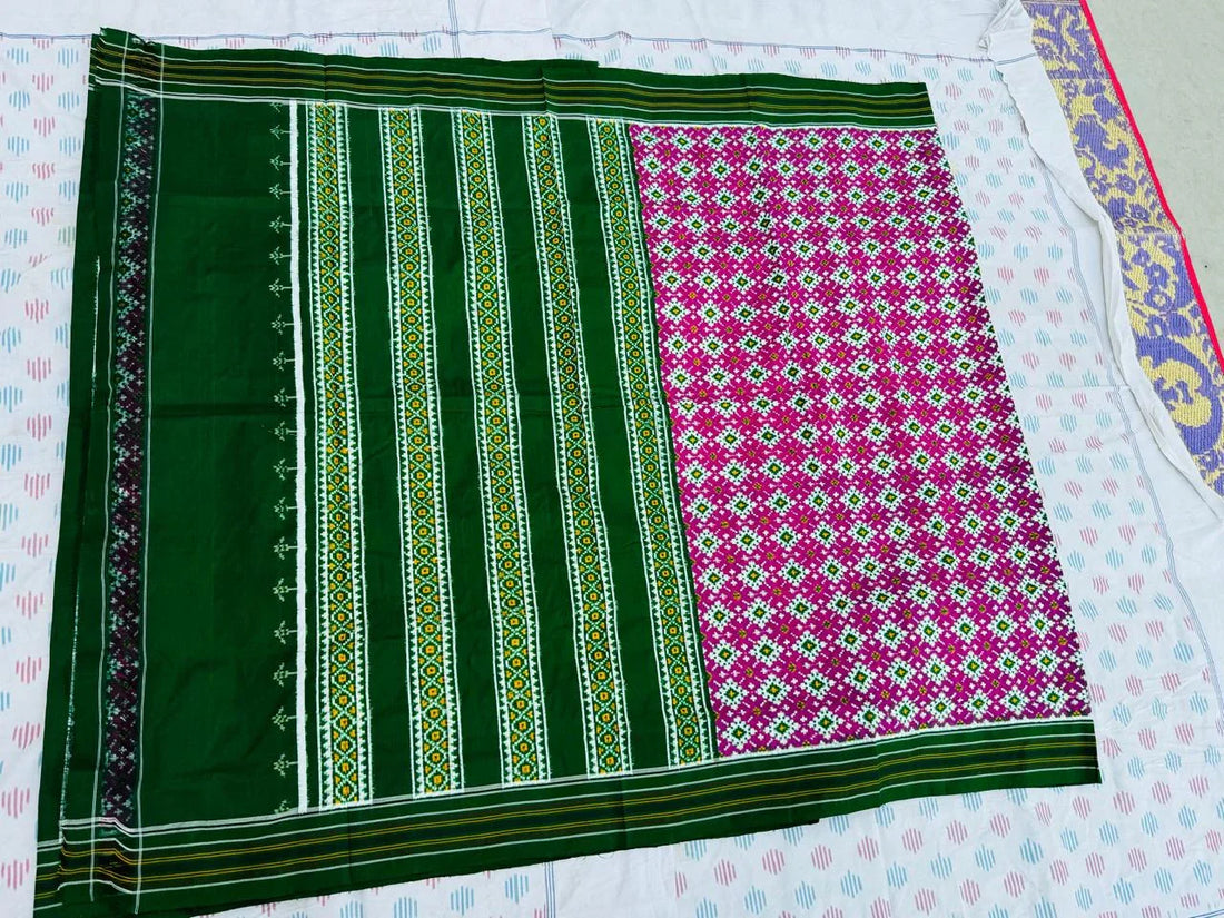 Flat lay of a pink double ikat patola silk saree featuring a contrasting dark green striped pallu and a Silk Mark certification