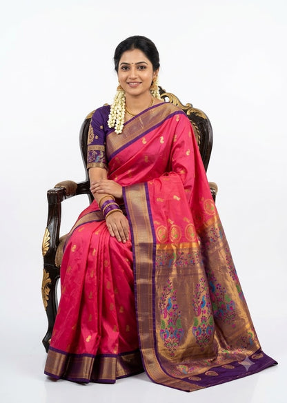 A beautiful traditional woman sitting on a chair wearing a vibrant pink Semi Gadwal saree with a contrasting purple golden zari border and matching purple blouse against a plain white background.