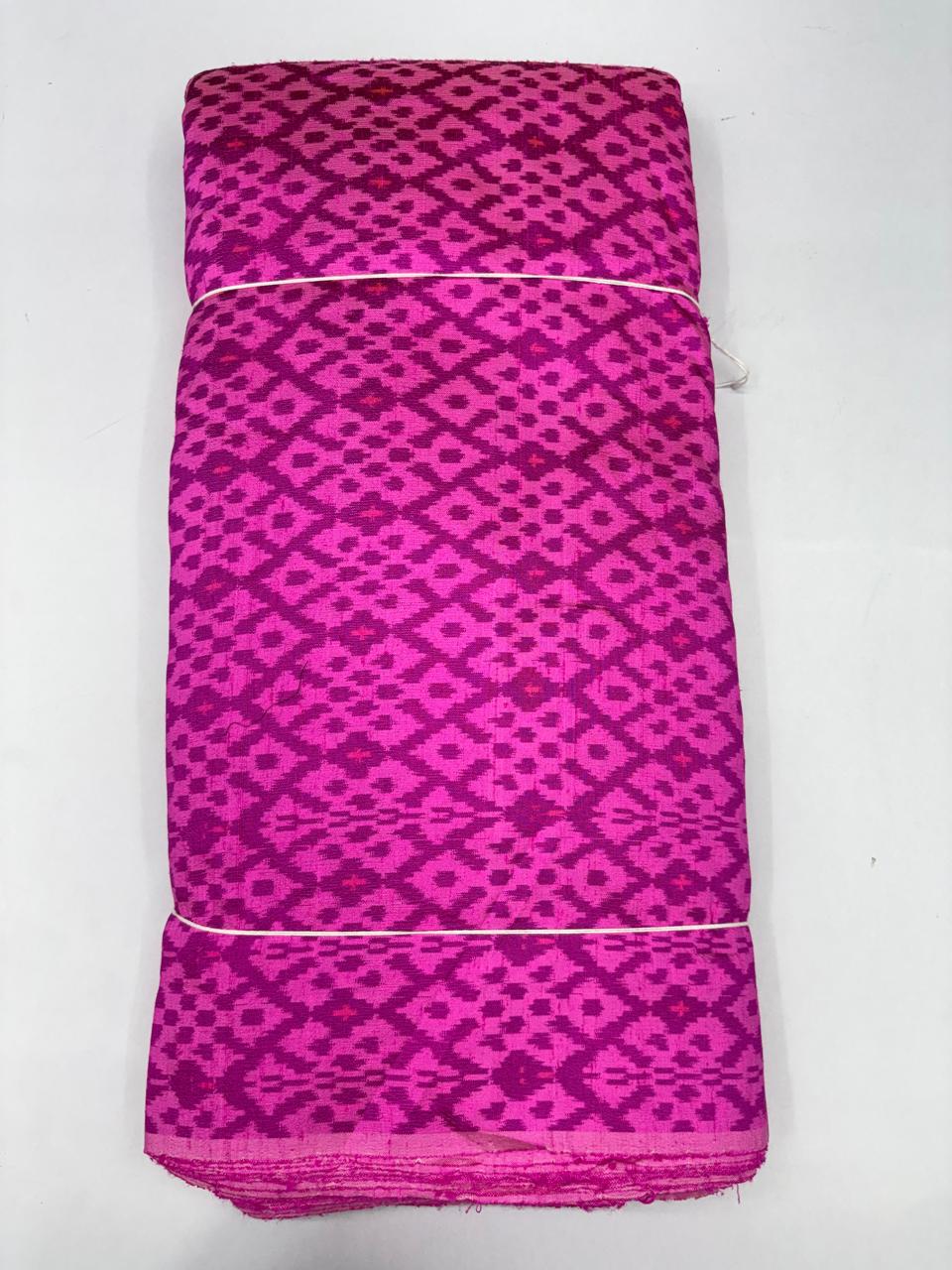 Folded bolt of vibrant rani pink pure raw silk fabric featuring an all-over geometric diamond jaal Ikat weave with Silk Mark authenticity